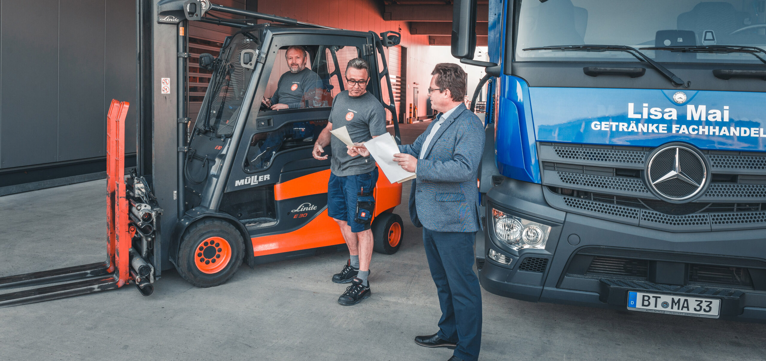 Gabelstapler und LKW im Hintergrund. Personen im Gespräch